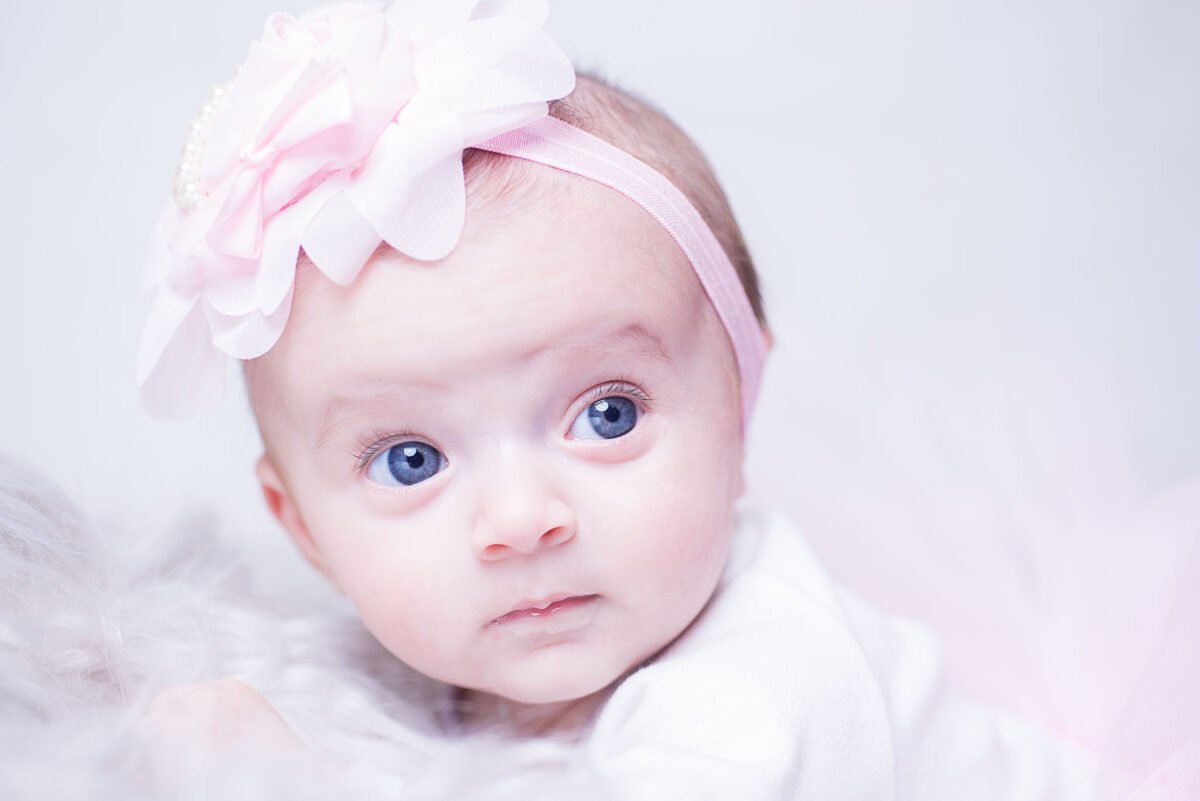 Un bébé avec un bandeau à fleurs roses photographié par un photographe à Perpignan.
