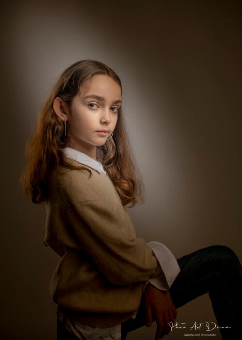 Une jeune fille pose devant un fond sombre dans un studio de Perpignan.